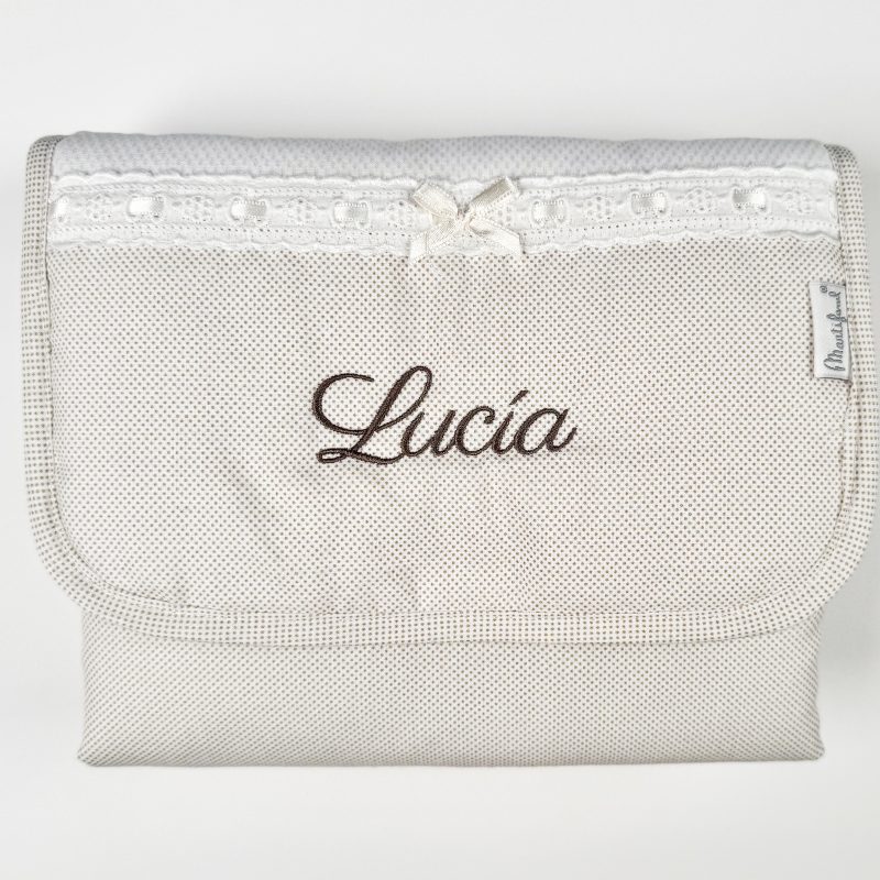 Cambiador de viaje para bebé con topitos en tono beige.